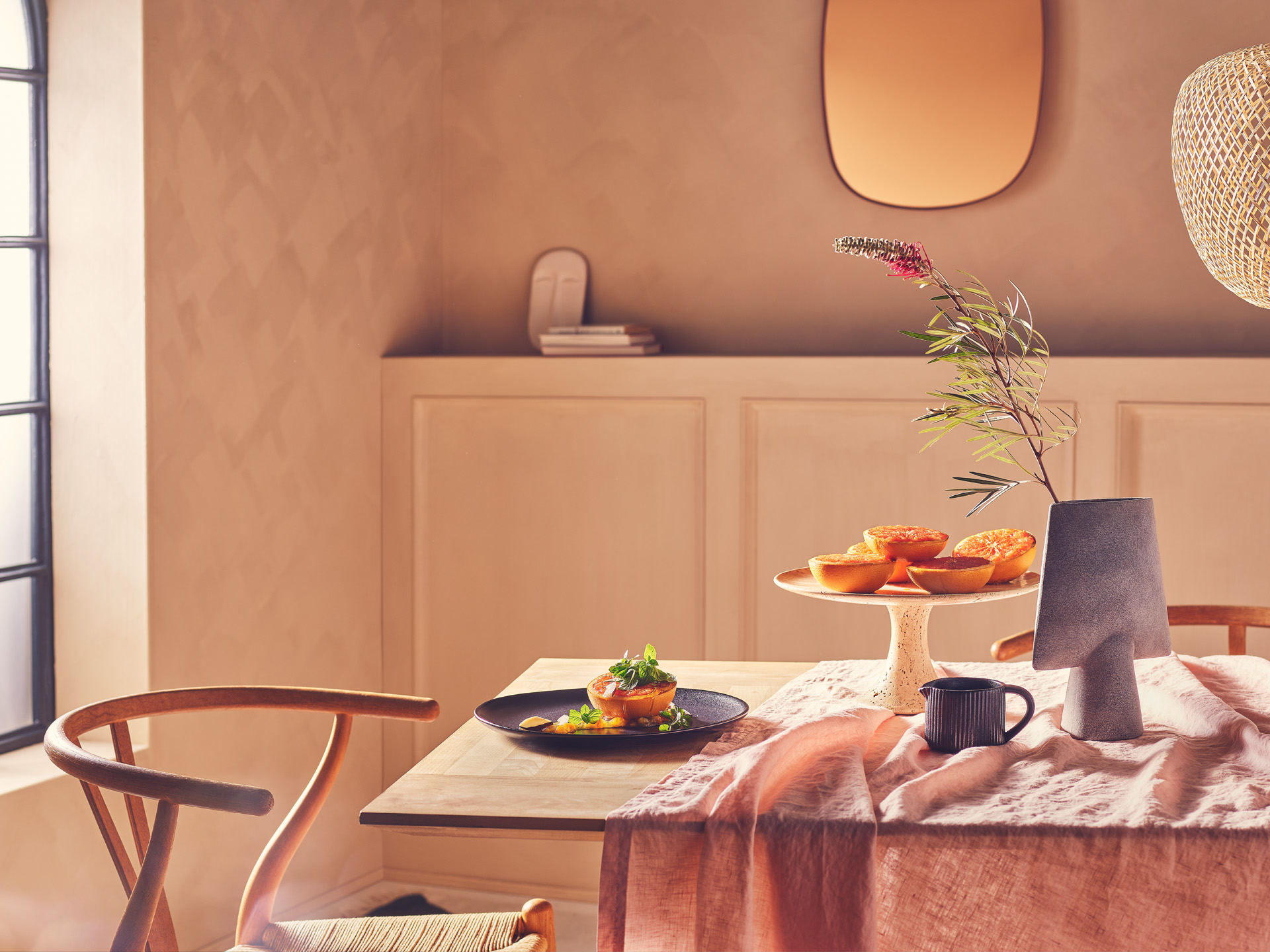 Fotostrecke mit Foodfokus: Karamellisierte Orange auf modern gestylten Tisch vor Fenster und Kommode mit freundlichem weichen Licht in räumlicher Atmosphäre und Tiefe - Konzeption, Artdirektion, Setbau und Werbefotografie durch das Studio Hackenberg in Kiel