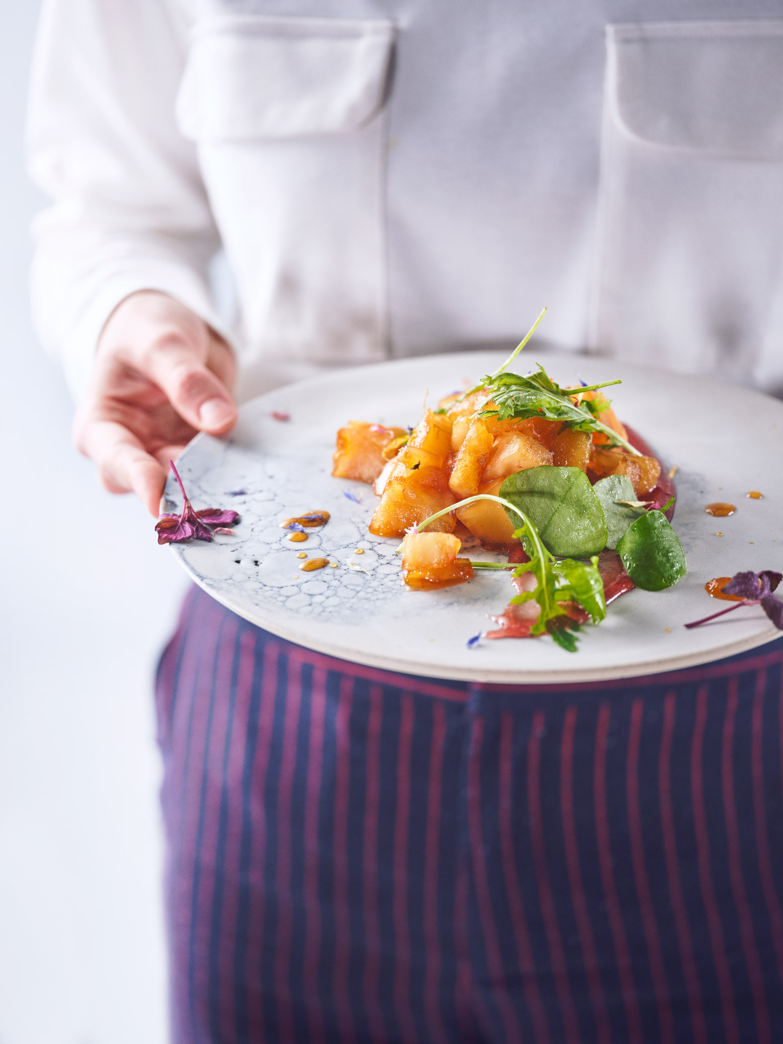 Eine Frau hält einen von einem Foodstylisten wunderschön angerichteten Teller mit Sellerie-Brunnenkresse-Salat | ein Beispiel für Foodstyling | Studio Hackenberg Foodfotograf und Regisseur